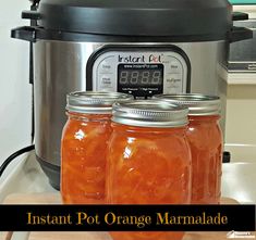 three jars filled with orange marmalade next to an instant pot