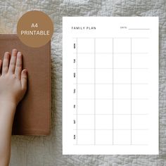 a person's hand on top of a planner next to a notebook with the text printable family plan