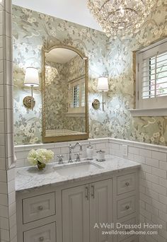 an image of a bathroom with marble counter tops and white cabinets, along with a large mirror above the sink