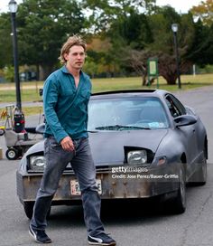 a man standing next to a car in the street