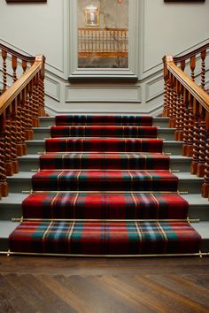 the stairs are lined with plaid carpet and wooden handrails, along with pictures on the wall