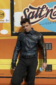 a man dressed in leather standing next to a food truck with his hands on his hips