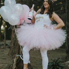 a woman in a pink tutu holding a bottle and some balloons