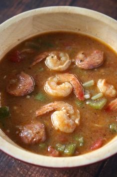 a bowl filled with soup and shrimp on top of a wooden table