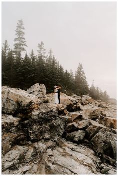 a man and woman standing on top of a rocky mountain