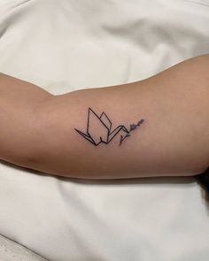 a person with a tattoo on their arm that looks like an origami bird