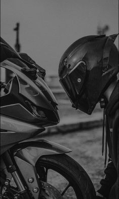 black and white photograph of a person wearing a helmet next to a motorcycle