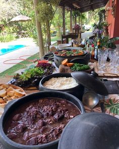 a table filled with lots of food on top of a wooden table next to a swimming pool