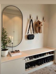 shoes are lined up on the wall in front of a mirror and coat rack with hooks