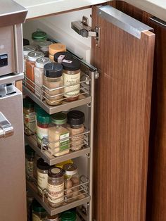 an open cabinet in a kitchen filled with spices