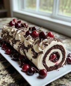 a piece of cake with cherries on it sitting on a plate next to a window