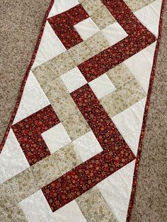 a red and white quilt is laying on the floor with it's edge down