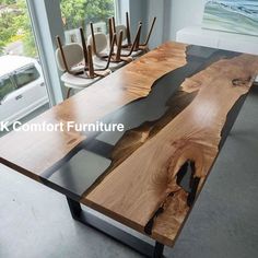 a table made out of wood and glass in a room with large windows overlooking the ocean