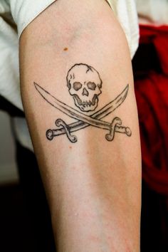 a skull and two crossed swords tattoo on the arm