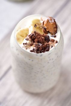 a close up of a milkshake in a glass on a table with bananas and chocolate