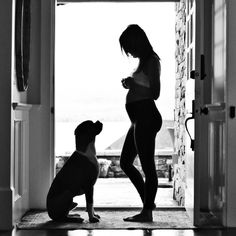 a pregnant woman standing in front of an open door with her dog