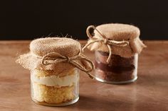 two jars filled with food sitting on top of a wooden table