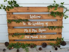 a wooden sign with greenery on it that says welcome to the wedding of mr and mrs byrne