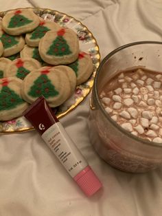 a plate of cookies next to a cup of hot chocolate with marshmallows