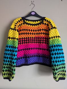 a multicolored sweater hanging up on a wall with a hanger in front of it