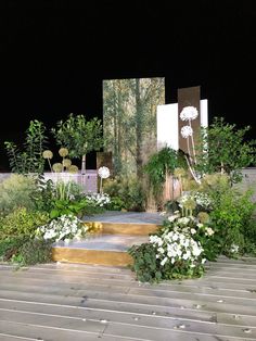 an outdoor garden at night with white flowers and greenery on the steps leading up to it