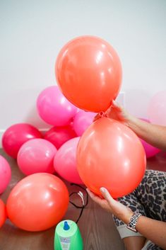 a woman is holding balloons in front of pink and orange balls on the floor,