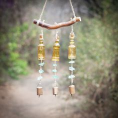 a wind chime hanging from a tree branch with glass beads and wooden tubes attached to it