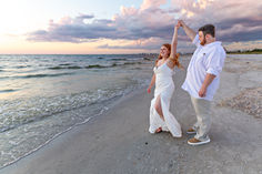 a man and woman dancing on the beach