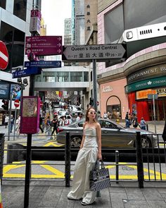 a woman is standing on the side walk