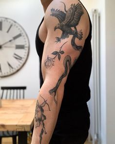 a man with a tattoo on his arm is standing in front of a wall clock