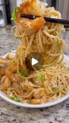 shrimp and noodle stir fry with chopsticks in a white bowl on a counter