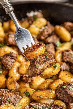 a fork with some food on it in a pan filled with potatoes and meats