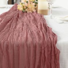 the table is covered with pink linens and flowers