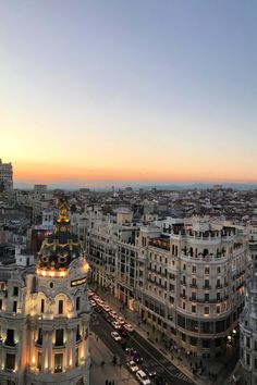 an aerial view of a city at dusk with cars and buildings in the foreground