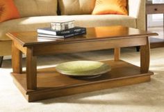 a coffee table with a green bowl on it in front of a beige couch and orange pillows