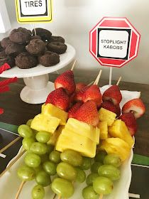 a table topped with lots of fruit and chocolate covered strawberries next to a stop sign