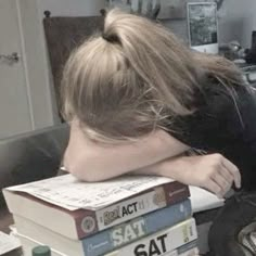 a woman leaning her head on stack of books