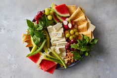 a plate filled with cheese, fruit and crackers