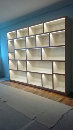 an empty room with a large bookcase in the middle and light shining on it