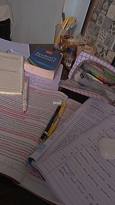 an open book on top of a desk with pens and pencils