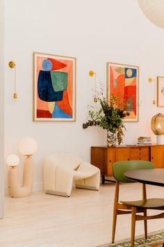 a living room filled with furniture and paintings on the wall