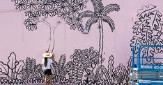 a person standing in front of a pink wall with black and white drawings on it