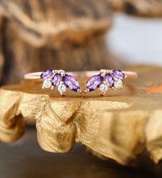 two amethorate and diamond rings on a gold plated surface with a wooden piece in the background