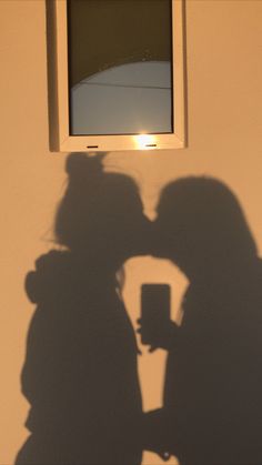 two people standing next to each other in front of a window with the sun shining through