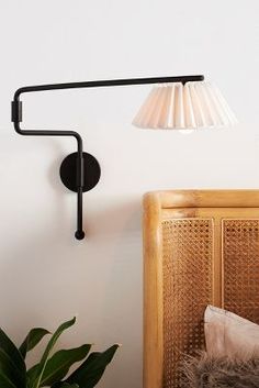 a black wall light next to a plant