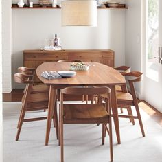 a dining room table with wooden chairs and a bowl of food on top of it