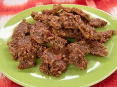 a green plate filled with meat on top of a red and white table cloth