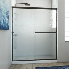 a bathroom with a shower and rugs on the floor in front of it's glass door