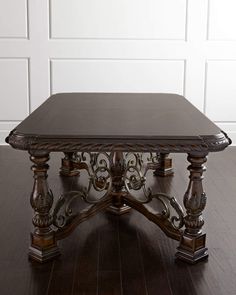 a wooden table sitting on top of a hard wood floor next to a white wall