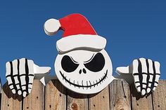 a wooden fence with a sign that has a skeleton on it and a santa hat